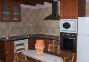 Cocina en madera con mesa delante y muchas sillas