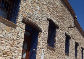 Acceso principal a la casa con la fachada de piedra y puerta de madera