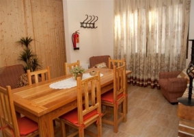 Sala de estar y comedor con una mesa de madera y chimenea delante