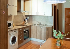 Cocina con mesa de madera y lavadora bajo la encimera