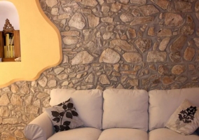 Sala de estar con sillones en blanco y paredes de piedra