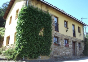 Acceso principal a la vivienda con fachada en amarillo y piedra