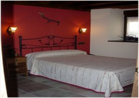 Habitación con cama matrimonial y pared roja de la casa rural