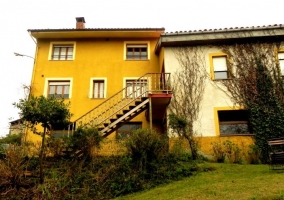 Acceso a la casa con fachada en amarillo y escaleras