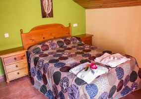 Dormitorio doble con un par de camas en morado y detalles de madera