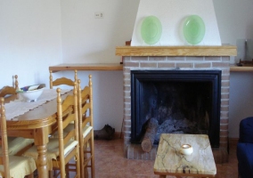 Sala de estar con la mesa de madera y la chimenea