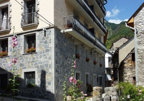 Acceso a la vivienda con fachada en piedra y balcones