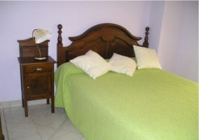 Dormitorio de la casa rural con cama matrimonial y colcha verde