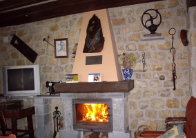 Sala de estar con chimenea encendida en piedra