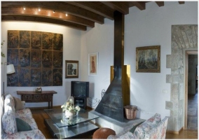 Sala de estar de la casa rural con chimenea, televisor y techos de madera