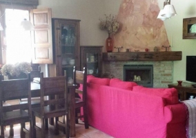 Sala de estar con mesa de comedor y la chimenea que hace esquina