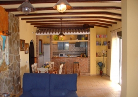 Sala de esrae con la cocina al fondo y su barra con taburetes