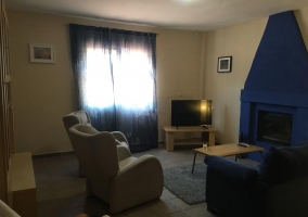 Sala de estar con chimenea de color azul y tele