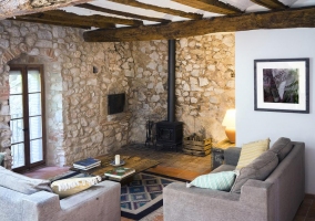 Sala de estar con chimenea de forja y pared de piedra