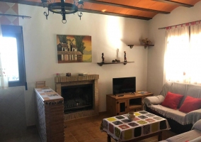 Sala de estar y zona de comedor con mesa de madera y alacena