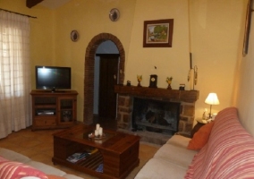 Salón con sillón en L, televisor y chimenea delante