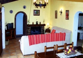 Salón comedor con sillón en L delante de la chimenea y el televisor