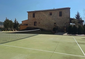 Amplia zona de tenis con fachada en piedra