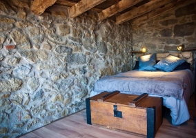 Habitación con cama de matrimonio y paredes en piedra