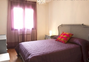 Habitación con cama de matrimonio morada totalmente amueblada