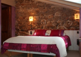 Suite con cama de matrimonio con paredes de piedra