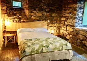 Habitación con cama de matrimonio con paredes de piedra