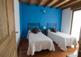 Dormitorio con dos camas pared azul