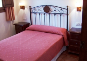 Dormitorio de matrimonio con colcha granate y dos mesitas de noche