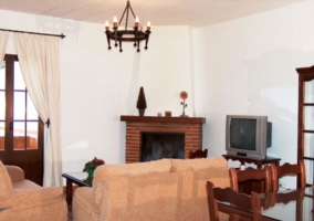 Salón con chimenea y televisor de la casa rural malagueña