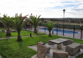 Jardín con mesa, piscina y palmeras