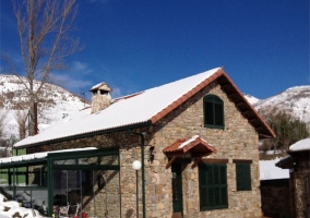 Fachada de la casa en piedra y pistas de tenis