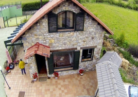 Fachada de la casa en piedra y pistas de tenis