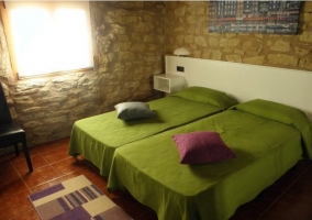 Dormitorio con dos camas y colchas rojas de la casa rural