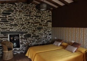 Dormitorio con silla de mimbre y dos camas de la casa rural