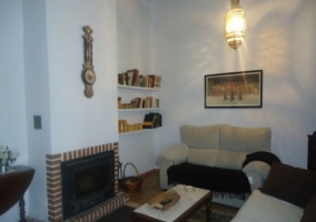 Sala de estar con chimenea y cuadros sobre los sillones