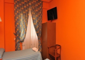 Dormitorio naranja con televisión