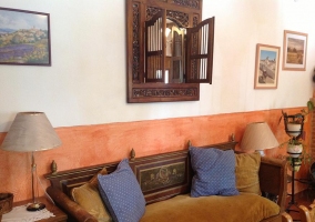 Sofá de la sala de estar con cojines de colores y espejo de madera tallada en la pared