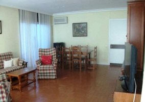 Salón con mesa de comedor y sofás de cuadros granates y verdes