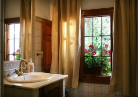 Cuarto de baño con cortinas y flores en el exterior