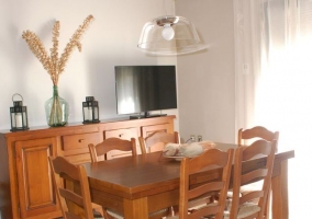 Mesa de comedor de madera y televisor de la casa rural