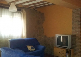 Salón con televisor y muros de piedra