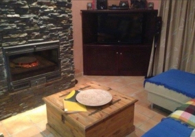 Sala de estar con sillones y chimenea con la mesa en madera