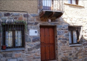 Acceso a la casa con fachada en piedra y puerta de madera