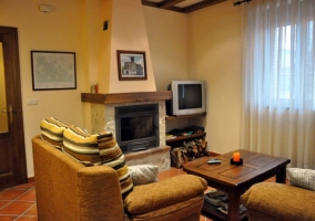 Sala de estar con dos sillones y televisor al lado de la chimenea