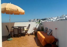 Terraza con sillón naranja y muebles de exterior